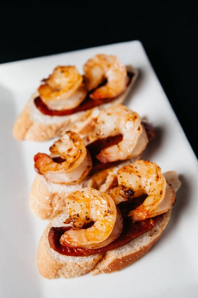 Plate of delicious  bruschetta with grilled shrimp and sausage o - Photo, Image