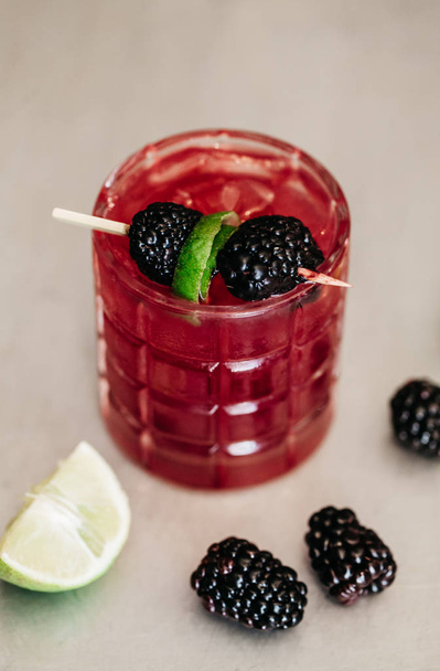 Summer alcoholic cocktail garnished with blackberries and lime - Photo, Image