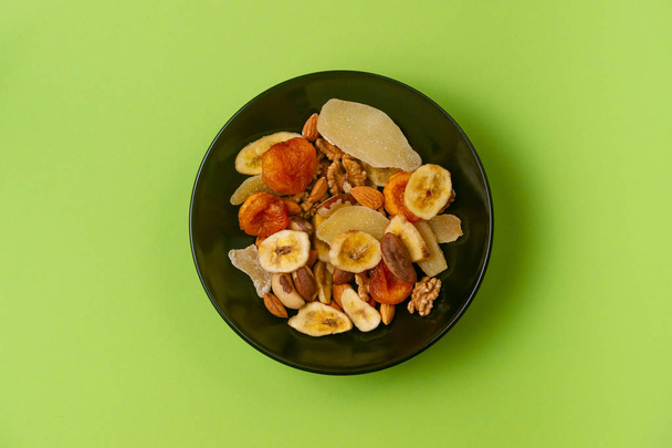 A fresh dried and candied fruits and nuts in black bowl on green - Φωτογραφία, εικόνα