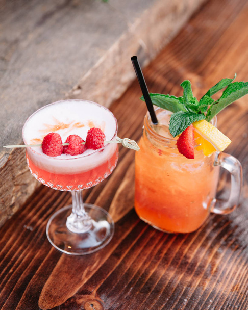Two alcoholic cocktails garnished with berries and mint  - Photo, Image
