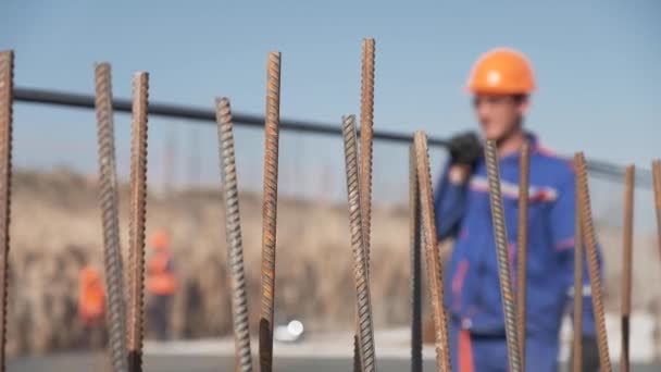 Bulanık adamlar inşaat alanında çelik takviye çubukları taşıyor. - Video, Çekim