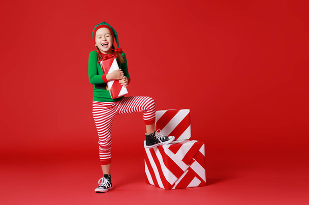 cheerful funny child in Christmas elf costume with gifts on   re - Photo, Image