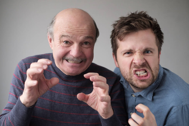 Angry mature father and son threating you lookign with dospleased expression at camera. - Photo, Image