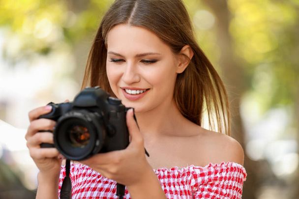 Kaunis naisvalokuvaaja kameran kanssa ulkona
 - Valokuva, kuva