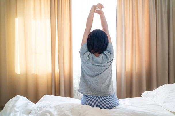 Donna che si estende a letto con le braccia in alto
 - Foto, immagini