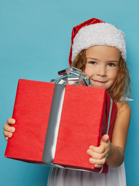  Girl in Santa red hat holding Christmas gift - Foto, Imagen