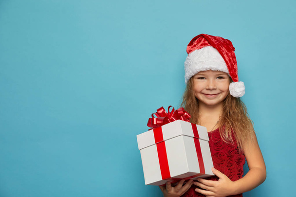  Girl in Santa red hat holding Christmas gift - Fotó, kép
