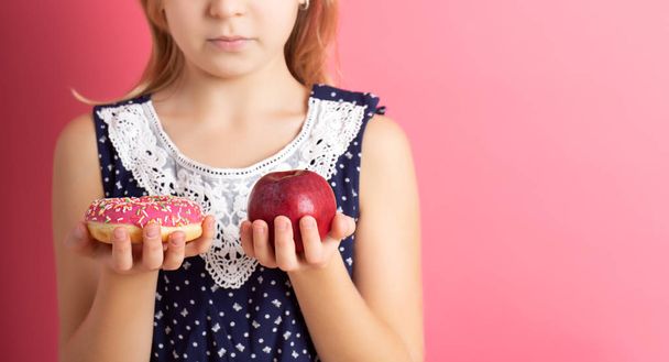Uma foto de uma mulher escolhendo entre maçã e donut
 - Foto, Imagem