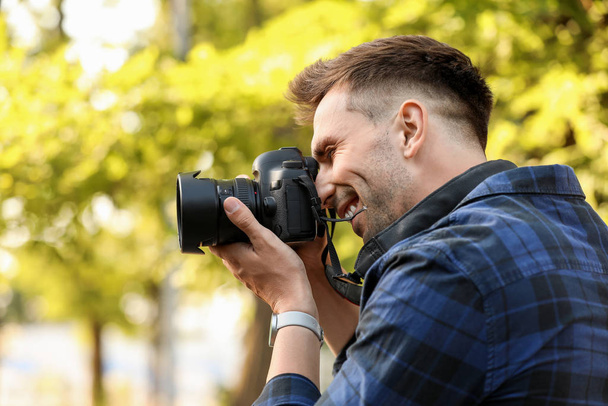 Knappe mannelijke fotograaf met camera buitenshuis - Foto, afbeelding