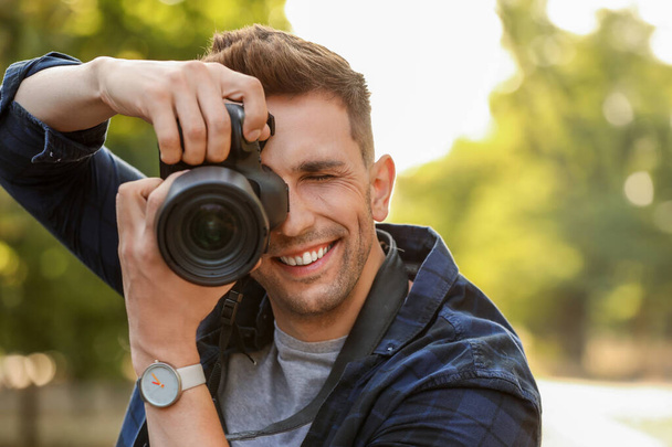 Όμορφος άντρας φωτογράφος με κάμερα σε εξωτερικούς χώρους - Φωτογραφία, εικόνα