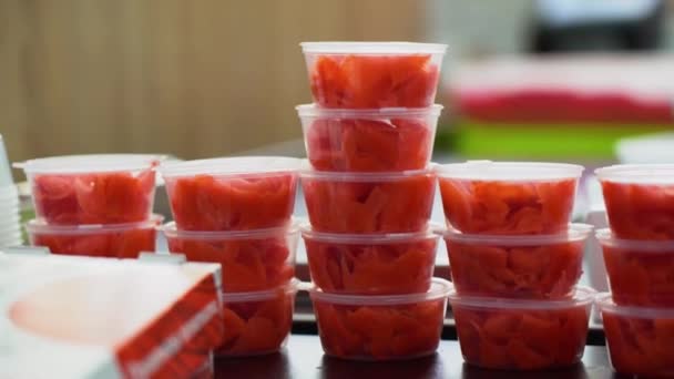 Sok ízletes főtt vörös gyömbér van csomagolva kis átlátszó dobozok, állva egymás tetején sushi tekercsek. A termék azonnal fogyasztható vagy eladható. - Felvétel, videó