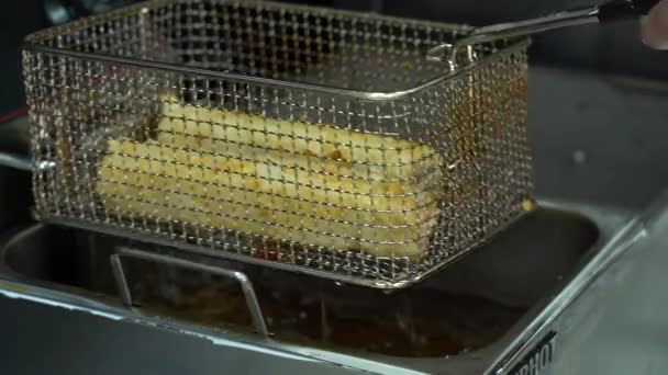 asiatische Köchin schüttelt das verbleibende fettige Öl ab und legt die leckeren gekochten Brötchen auf die silberfarbene Fritteuse. einer der vielen Stadien der Sushi-Zubereitung. - Filmmaterial, Video