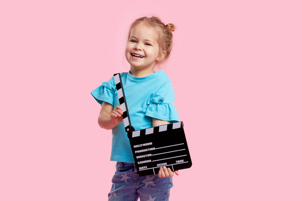 Funny smiling child girl in cinema glasses hold film making clapperboard isolated on pink background. Studio portrait. Childhood lifestyle concept. Copy space for tex - Fotoğraf, Görsel