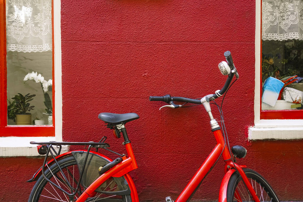 one Red bicycle parked outside a townhouse  between two windows  - Foto, immagini