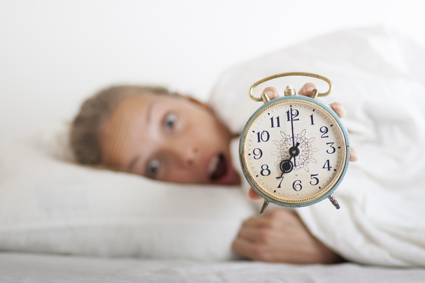 Young sleeping woman and alarm clock in bed - Valokuva, kuva