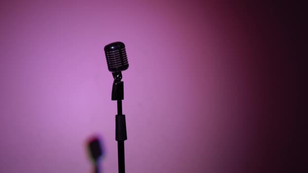 Concert vintage microfoon voor opname of spreken met publiek op het podium in donkere lege retro club. Flitsen van schijnwerpers knipperen elke seconde, van kleur veranderen. Chrome microfoon op multi kleur achtergrond. - Video