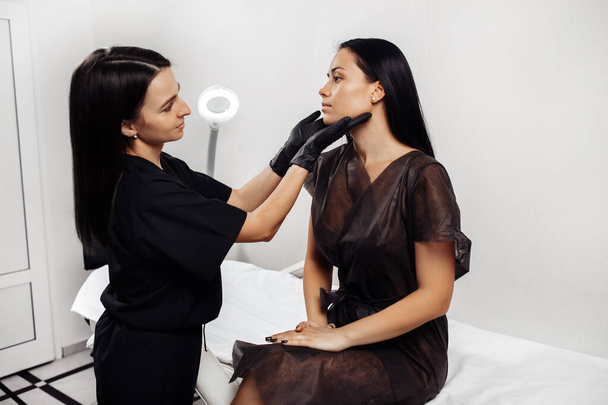 Professional female cosmetologist examining face skin of beautiful woman. - Foto, Imagem