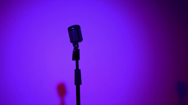 Επαγγελματική συναυλία vintage glare μικρόφωνο για εγγραφή ή να μιλήσει στο κοινό στη σκηνή σε άδειο ρετρό club close up. Μπλε χρώμα από τα φώτα της δημοσιότητας κοπή αλλαγές σε μπορντό γκρι σε σκούρο φόντο. - Πλάνα, βίντεο