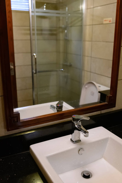 koupelna s bílým umyvadlem s chromovým kohoutkem v hotelovém pokoji - Fotografie, Obrázek