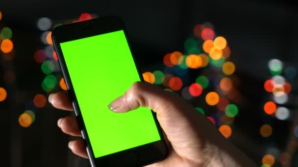 Woman holds a smartphone with a green screen and scrolls. Hand with phone close-up - Footage, Video