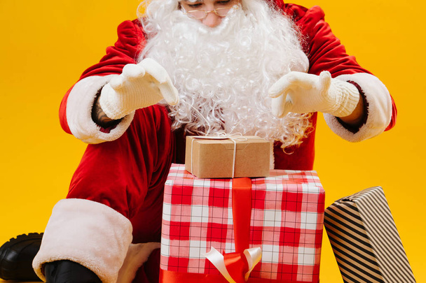 Santa knotting ribbons on a box with a gift - Photo, image