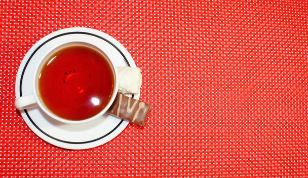 Marmeládé édességek cukorban, karamellában és egy csésze teában. - Fotó, kép