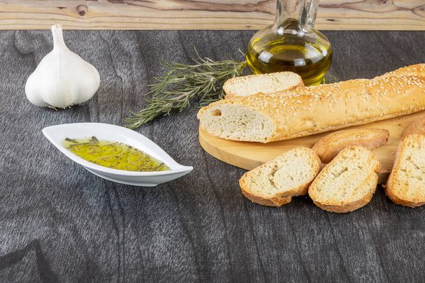 Baguette et trempette à l'huile d'olive. Délicieux snack grec et boissons. Huile d'olive aux herbes et ail. Sauce à l'huile d'olive au pain sur fond bois
.  - Photo, image