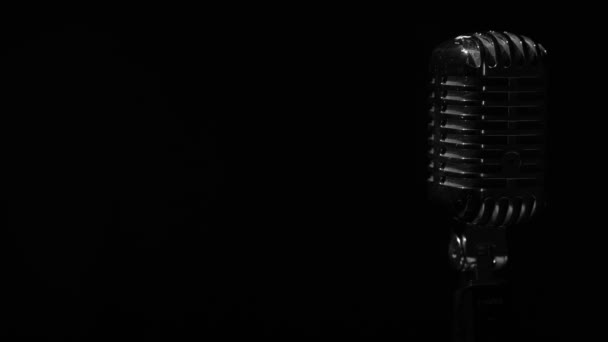 Profesionální koncertní vintage oslnivý mikrofon pro záznam nebo mluvit s diváky na jevišti v temném prázdném klubu zblízka. Bílé reflektory svítí na chrom retro mikrofon vpravo na černém pozadí. - Záběry, video