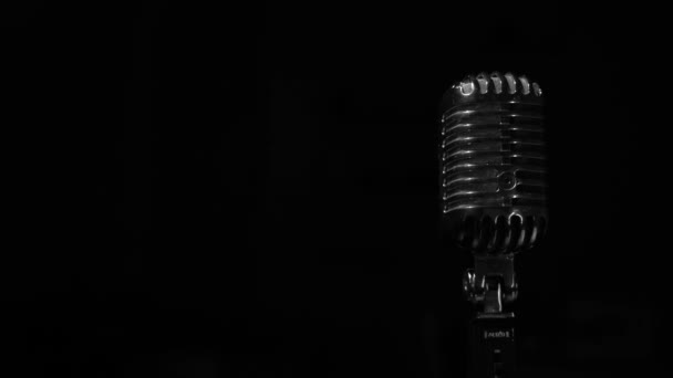 Glans van wit licht flikkert en schijnt op een chromen retro microfoon op een zwarte achtergrond. Professionele vintage glare microfoon voor opnemen of spreken met publiek op het podium in donkere lege club close-up. - Video