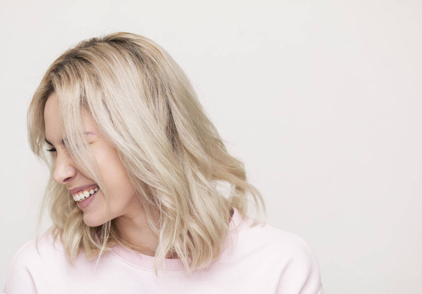mooi meisje lachen op camera, spelen en plezier hebben, mooi blond op een roze achtergrond - Foto, afbeelding