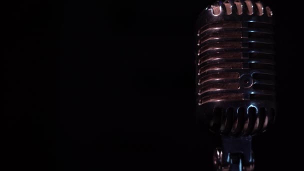 Professionele vintage verblindende microfoon voor opname of spreken tot publiek op het podium in donkere lege ruimte close-up. Rood-witte spots schijnen op een chromen retro microfoon aan de rechterkant op zwarte achtergrond. - Video