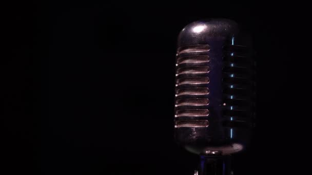 Επαγγελματικό κλασικό vintage μικρόφωνο glare για εγγραφή ή να μιλήσετε με το κοινό στη σκηνή σε σκοτεινό άδειο club close up. Οι προβολείς λάμπουν σε ένα χρωμιωμένο ρετρό μικρόφωνο με κόκκινη και μπλε φωτοβολίδα σε μαύρο φόντο. - Πλάνα, βίντεο