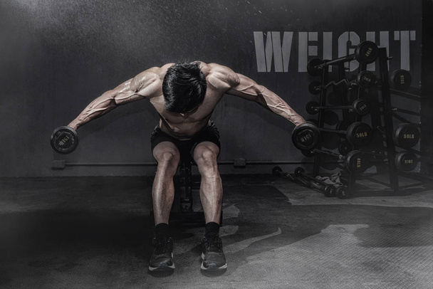 Forte homem de fitness fazendo treino de braço com halteres no ginásio
 - Foto, Imagem
