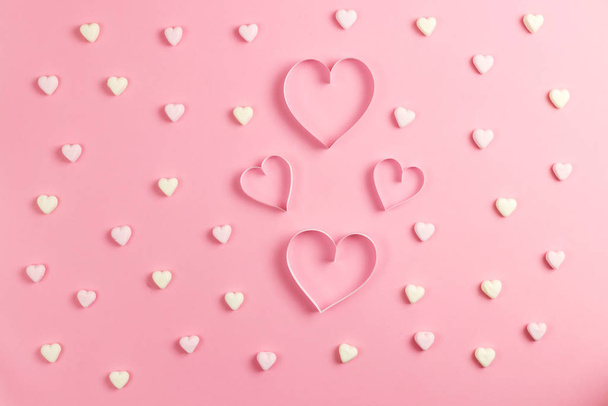 Composition for Valentines Day February 14th. Delicate pink background and a heart cut out of paper. Heart shaped yellow and pink marshmallows. Greeting card. Flat lay, top view, copy space - Foto, Imagem