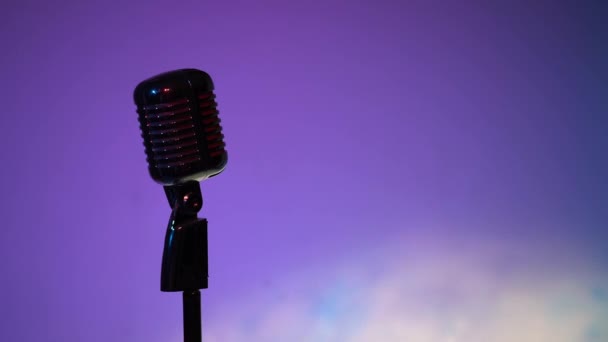 La lumière des projecteurs réglables et réglables sur un micro chromé sur fond lumineux. Microphone vintage argenté éblouissant pour enregistrement ou parler au public sur scène dans un club rétro sombre vide gros plan
.  - Séquence, vidéo