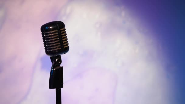 Професійний срібний старовинний відблиск мікрофон для запису або розмови з аудиторією на сцені в темному порожньому ретро-клубі крупним планом. Точкові світильники сяють на хромованому мікрофоні з підсвічуванням на фантастичному фоні
. - Кадри, відео
