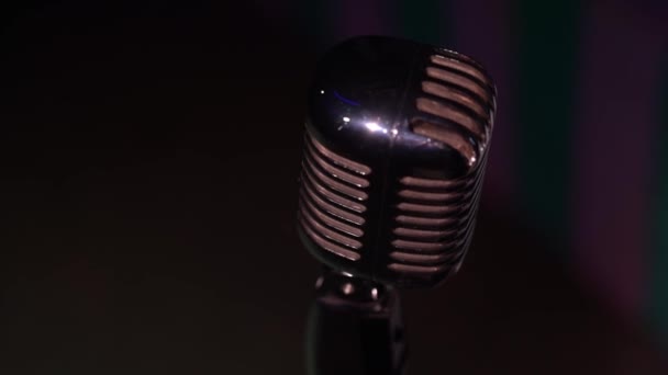 View from above on silver retro glare microphone for record or speak on scene in dark empty club close up. Spotlights shine on a chrome retro mic with highlights on black background. Top view. - Footage, Video