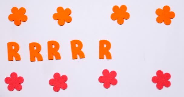 Oranssi R-kirjain lentää puolelta toiselle. Ylä- ja alareunan kukat liikkuvat
. - Materiaali, video
