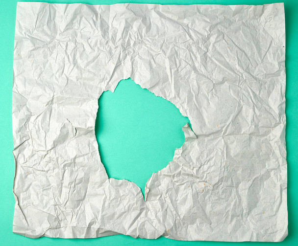 feuille de papier grise froissée avec un trou, support vert
 - Photo, image