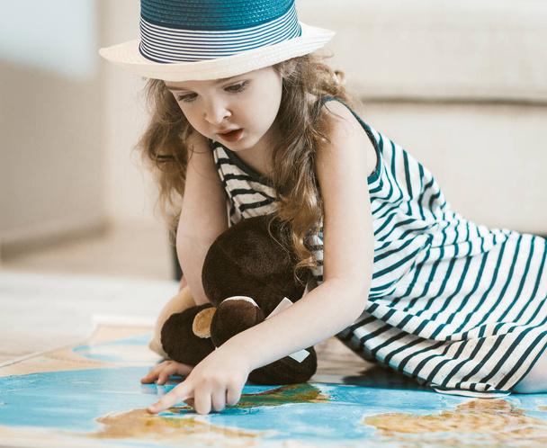 Little girl with her toy studying map, going on vacation with parents. - Foto, afbeelding