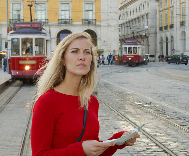 Attractive woman checks directions on the map om the city of Lisbon - CITY OF LISBON, PORTUGAL - OCTOBER 15, 2019 - Foto, Imagen
