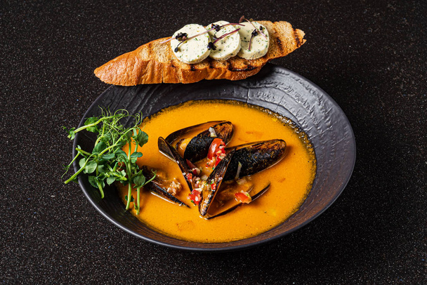 seafood soup with toast on the black background - Foto, afbeelding