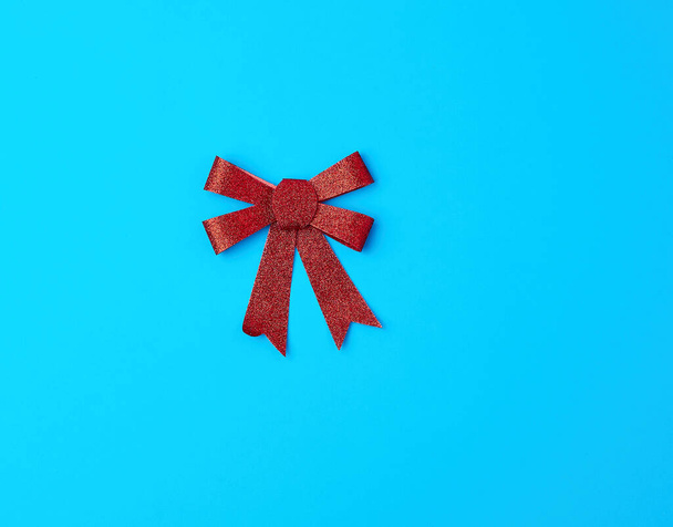 red shiny bow for decoration gifts on a blue background - Фото, зображення