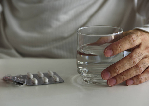 Чоловічий пацієнт тримає склянку води для прийому ліків
 - Фото, зображення