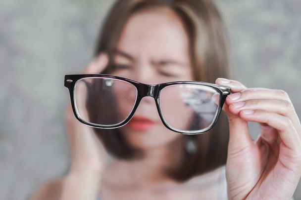 眼鏡を持っているアジアの女性は、目のぼやけのビジョンに問題がある  - 写真・画像