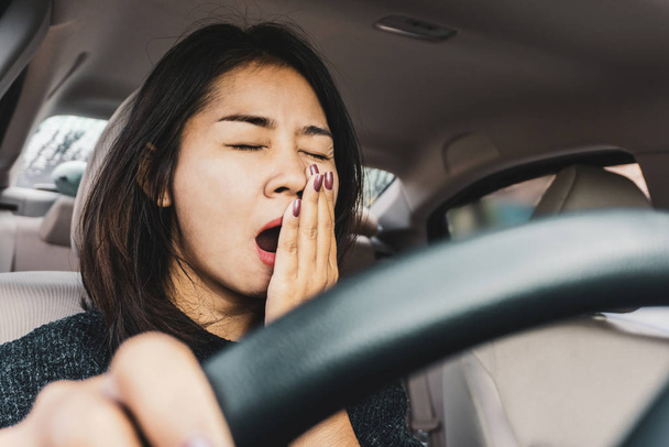 Уставшая сонная азиатка зевает во время вождения автомобиля
  - Фото, изображение