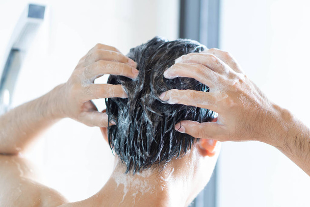 Nahaufnahme junger Mann beim Haarewaschen mit Shampoo im Badezimmer, Vintage-Ton, selektiver Fokus - Foto, Bild