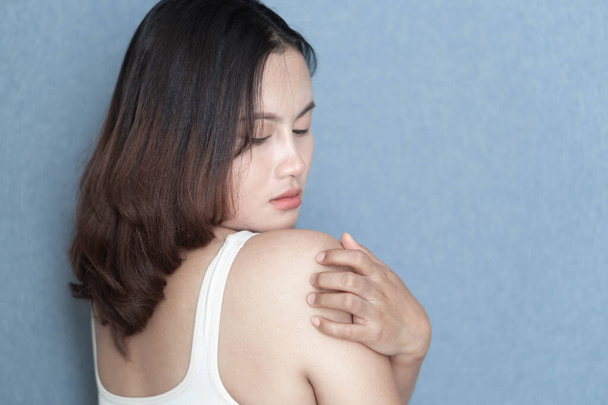 Mano de mujer rascándose el hombro con fondo gris, cuidado de la salud y concepto médico
 - Foto, Imagen