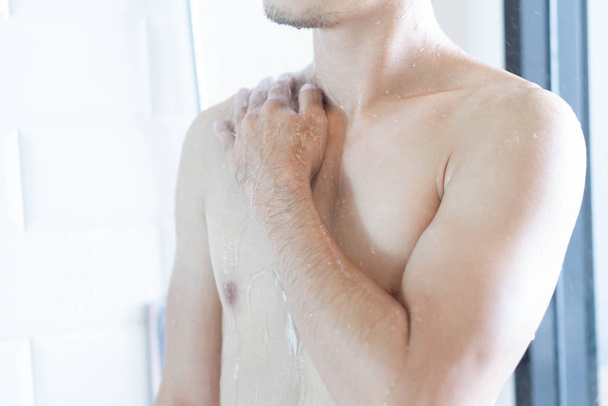 Closeup handsome asian man taking a shower in the bathroom, selective focus - 写真・画像
