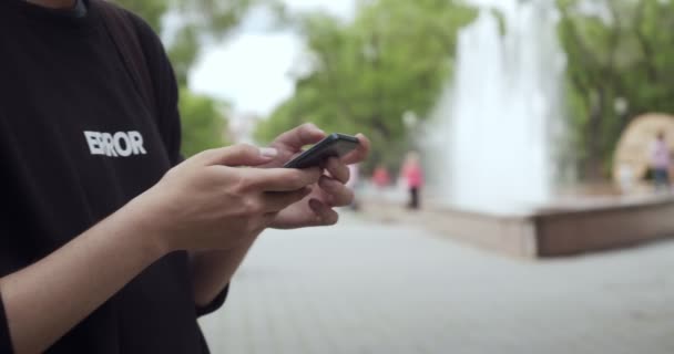 Hands of young man using smartphone outdoors. - Кадри, відео